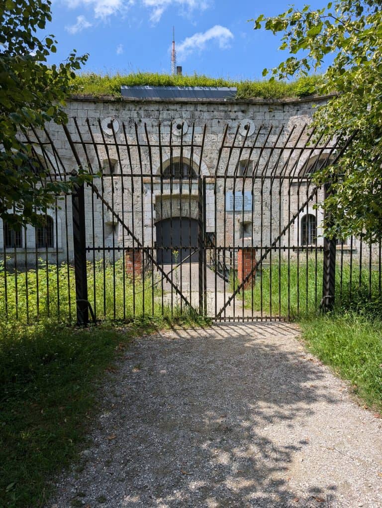 Eingangstor mit grünbewachsenem Hauptgebäude