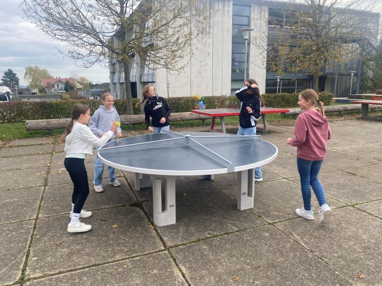 Schülerinnen spielen an einer runden Tischtennisplatte