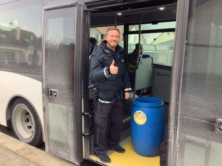Polizist lächelt mit Daumen hoch und im Bus stehend
